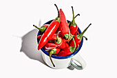Top view of big ceramic mug full of ripe fresh exotic pepper placed on white background