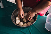 From above of crop unrecognizable ethnic female preparing soft dough in bowl at table in kitchen