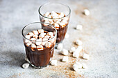 Hot chocolate with mini marshmallow in the glass on concrete background
