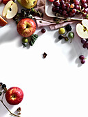 Composition with fresh summer fruits and berries on white background. Grapes, plums and apples in sunlight.