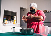 Venezuelan female in cloth face mask preparing arepas at table with bowl at home