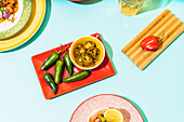 From above raw and marinated jalapenos placed on red plate on blue background