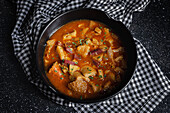 From above of tasty callos a la madrilena in black bowl on table with napkin