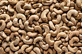 Full frame top view of huge amount of raw tasty cashews placed on smooth surface