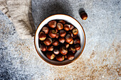 From above bowl full of tasty fresh hazelnut on concrete background