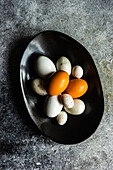 Bowl with multicolor chicken eggs and quail eggs as a spring Easter concept on concrete background