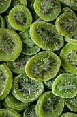 Full frame top view of pile of sliced sweet green dry kiwi with sugar placed on surface