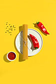 From above appetizing fresh dry spaghetti with red sauce and spice dip red peppers on yellow background