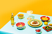 Dishware with nachos and chicken salad placed near bottle of beer and glass of lemonade against yellow background
