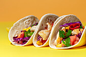 Hausgemachte mexikanische Tacos mit frischem Gemüse und Huhn mit starkem Licht auf gelbem Hintergrund. Gesundes Essen. Typisch mexikanisch
