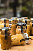 Closeup of many closed glass bottles with fresh yellow homemade blended vegetable mix inside placed on table