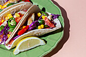 Homemade Mexican Tacos with fresh vegetables and chicken with strong light on pink background. Healthy food. Typical Mexican