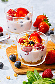Delicious homemade yogurt with strawberries, berries and cereals on white background