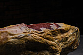 Leckere trocken gepökelte spanische Schweinekeule auf Holzständer auf grauem Untergrund