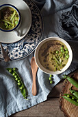 Closeup of served bowls with green pea and coconut cream soup on table