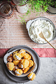 From above bowl with crunchy nun's puffs bites stuffed with cream cheese placed on table in kitchen at home