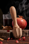 Fresh whole pomegranate and seeds arranged on wooden board near squeezer