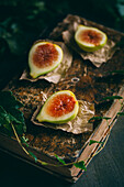 Top view of fresh sweet figs arranged on wooden chopping board with green leaves