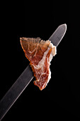 schmackhafte dünne, trocken gepökelte iberische Jamon-Scheibe mit angenehmem Aroma und eingerissenen Rändern