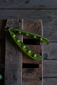 From above closeup view of fresh opened pod with shiny peas on wood