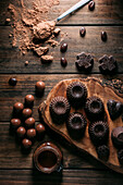 From above set of tasty handmade chocolates placed on wooden cutting board near mousse jar in kitchen