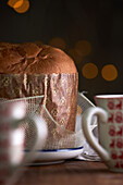 Ungeschnittener, frisch gebackener, handwerklich hergestellter Weihnachts-Panettone-Kuchen unter warmem Licht vor Bokeh-Hintergrund