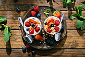 From above top view of delicious homemade yogurt with strawberries, berries and cereals on wooden table background