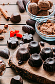 Various handmade chocolates with nuts arranged on wooden table with cinnamon sticks