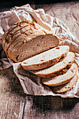 Von oben auf Scheiben von frisch gebackenem Vollkornbrot, die auf einem alten, schäbigen Holztisch in der Küche verstreut sind