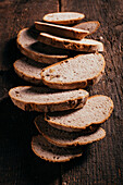 From above of slices of freshly baked wholegrain bread scattered on aged shabby wooden table in kitchen