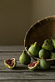 Closeup shot of basket with green figs and split fruit with red flesh on table