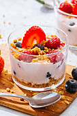 Close up of delicious homemade yogurt with strawberries, berries and cereals on white background