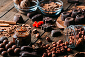 Various handmade chocolates with nuts arranged on wooden table with peanut butter and cinnamon sticks