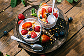 Blick von oben auf köstlichen hausgemachten Joghurt mit Erdbeeren, Beeren und Müsli auf Holztisch Hintergrund
