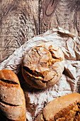 Draufsicht auf frisch gebackene leckere Sauerteigbrote in verschiedenen Formen auf einem Holztisch in einer Bäckerei