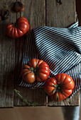 From above of ripe red tomatoes with striped napkin on wooden table