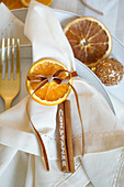 Napkin decoration with orange slice and cinnamon stick as name tag