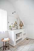 Bright bathroom with sloped ceiling, towels in open washbasin cabinet