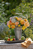 Blumenstrauss aus Rosen (Rosa), Dahlien (Dahlia), wilde Möhre in Zinkkrug dekoriert mit Aprikosen und Birnen