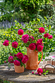 Bouquet of bourbon rose 'Vivid' (Rosa bourbonica) in a stone jar on the terrace