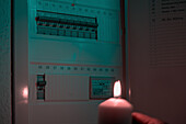 Hand holding candle near fuse box