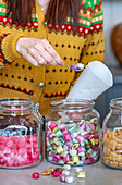 Woman filling sweets from glass containers into paper bags