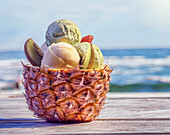 Pistachio and mango ice cream with kiwi served in half a pineapple