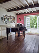 Piano in light-flooded room with gallery wall and open doors to the garden