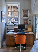 Vintage home office with antique wooden desk and orange office chair