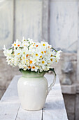Bouquet of daffodils (Narcissus) in antique jug on wooden table