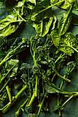 Spinach leaves and broccolini on a green surface