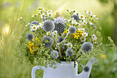 Colourful summer bouquet with globe thistles (Echinops) in an old teapot