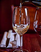 Weißwein wird in ein Glas eingeschenkt
