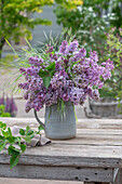 Blumenstrauß aus Fliederblüten (Syringa Vulgaris) und Gräsern im Eimer